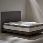 Un matelas avec Âme ressorts ensachés Springsac dont 7 zones de confort. Et tête de lit en tissu gris effet texturé.